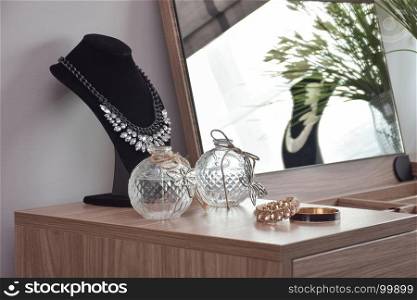 Bangles necklace and crystal jars on wooden dressing table