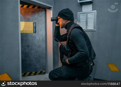 Bank robbery, male robber in black uniform holds gun and lantern. Criminal profession full of risk. Theft of money and jewels concept. Male robber in black uniform holds gun and lantern
