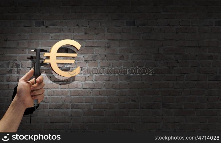 Banking and currency. Close up of hand measuring euro sign with wrench