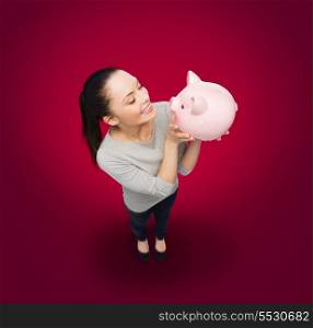 banking and investment concept - smiling woman looking at piggy bank