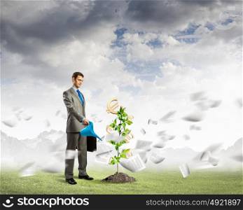 Banking concept. Image of young businessman watering money tree with euro symbols