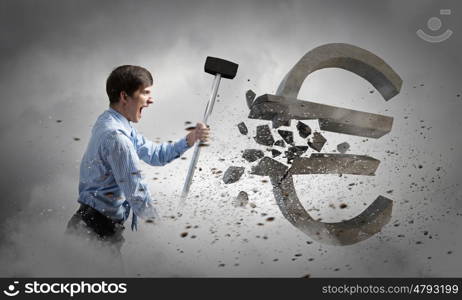 Banking concept. Young businessman crashing with hammer stone euro symbol