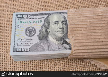 Banknote bundle of US dollar partly wrapped in cardboard