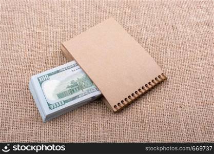 Banknote bundle of US dollar placed on a notebook