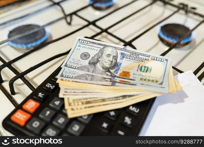 Banknotes lie next to a burning gas burner along with a calculator. The concept is to increase the cost of supply and payment for natural gas. Banknotes lie next to a burning gas burner along with a calculator. The concept is to increase the cost of supply and payment for natural gas.