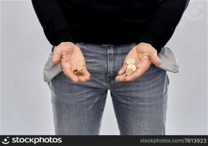 bankruptcy, financial crisis and poverty concept - close up of man showing hands with euro money coins and empty pockets over grey background. close up of man showing coins and empty pockets