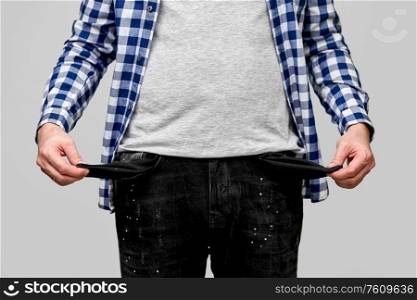 bankruptcy, financial crisis and poverty concept - close up of man showing empty pockets over gre. close up of man showing empty pockets