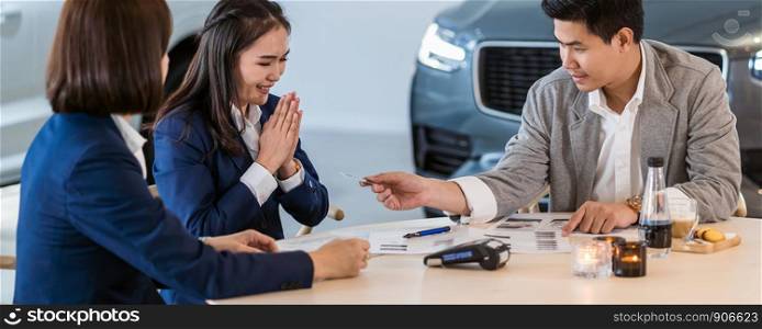 Banner and cover scene of Asian customer giving the credit card to sales representative for purchase new car after sign contract and agreement in the showroom, Customer service and sales car concept