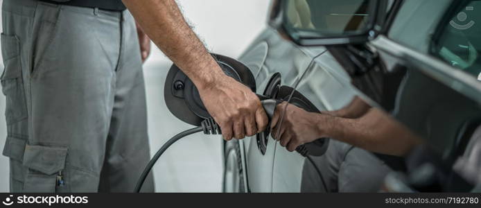 Banner and cover scene ofCloseup hand of technicial charging the car electrict in maintainance service center which is a part of showroom, economic and technology for safe the world concept