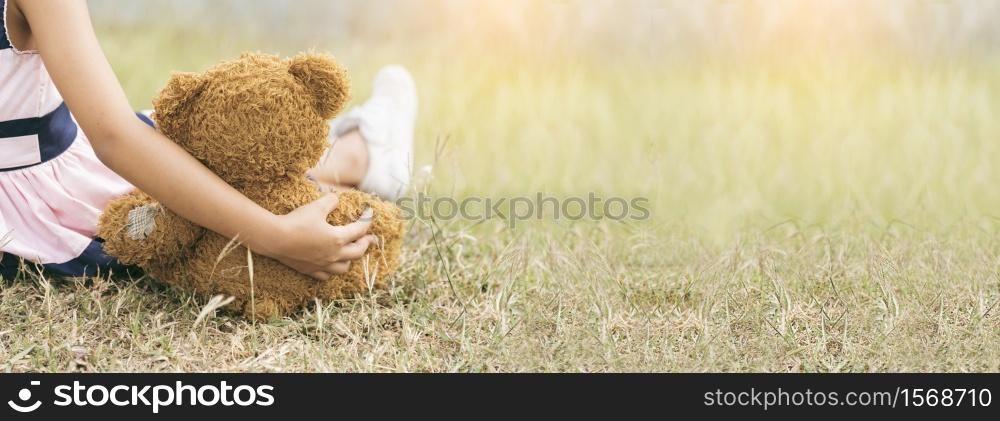 Banner Happy Child hug teddy bear in green park playground. Teddy bear best friend for little girl. Autism happy playing together on playground in happiness family feel love warm hugs with copy space