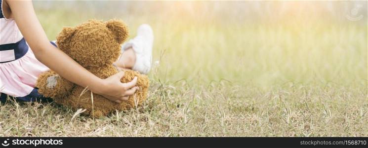 Banner Happy Child hug teddy bear in green park playground. Teddy bear best friend for little girl. Autism happy playing together on playground in happiness family feel love warm hugs with copy space