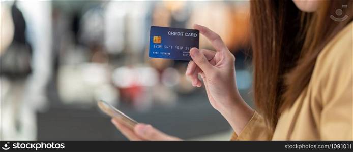 banner of Asian woman using credit card with mobile phone for online shopping in department store over the clothes shop store, technology money wallet and online payment concept, credit card mockup