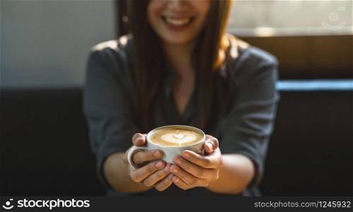 Banner of Asian young female holding a cup of coffee in modern coffee shop or coworking space beside window mirror, Lifestyle and leisure with hobby and entrepreneur concept, banner or web cover scale