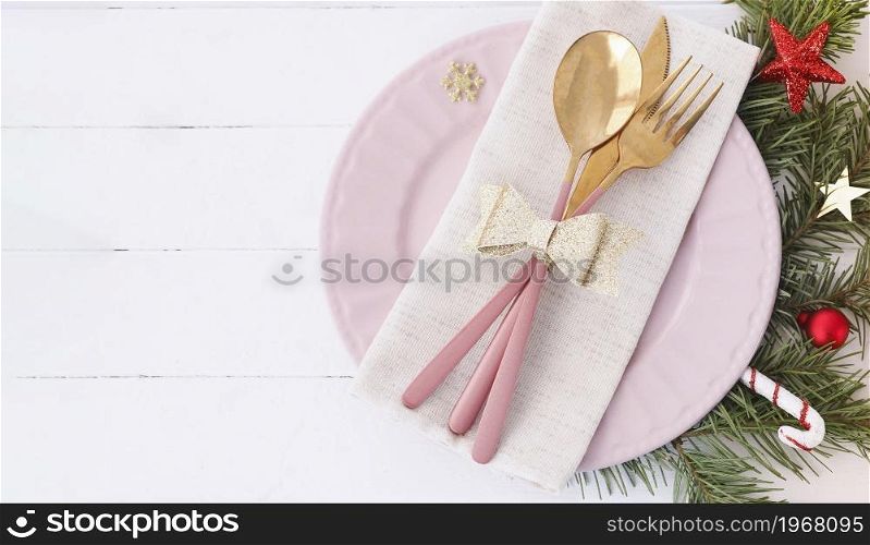 banner of Christmas table setting. pink plate, cutlery with gold bow, fir branches and stars. copy space.