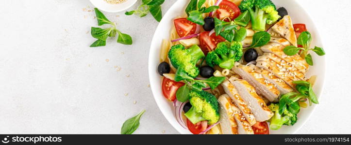 Banner. Pasta salad bowl with broccoli, tomato, onion, olives, corn salad and grilled chicken breast for lunch. Healthy dietary food. Top view.