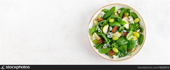 Banner. Salad of spinach, pear, grape, pecan and gorgonzola cheese with lemon dressing. Healthy food, diet. Top view.