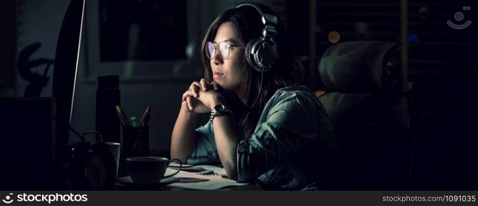 Banner, web page or cover template of Asian Businesswoman sitting and working hard on the table with front of computer desktop in office or workplace with over time, Work hard and too late concept