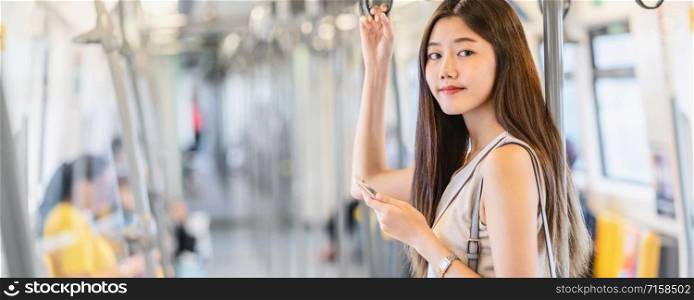 Banner, web page or cover template of Asian woman passenger using social network via smart mobile phone in subway train when traveling in big city,japanese,chinese,Korean lifestyle concept