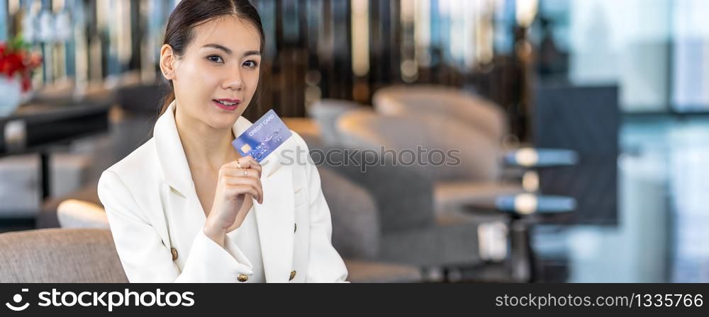 Banner, web page or cover template of Portrait Asian woman using credit card for online shopping in modern lobby or working space,technology money wallet and online payment concept, credit card mockup