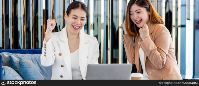 Banner, web page or cover template of Two asian businesswomen hapiness celebrating together when checking success goal via technology laptop in modern office or coworking space, relaxing and talking