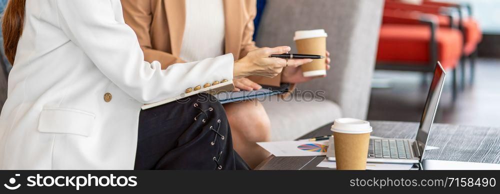 Banner, web page or cover template of Two asian businesswomen working with the partner business by point pen to the technology laptop in modern office or coworking space,partner and colleague concept