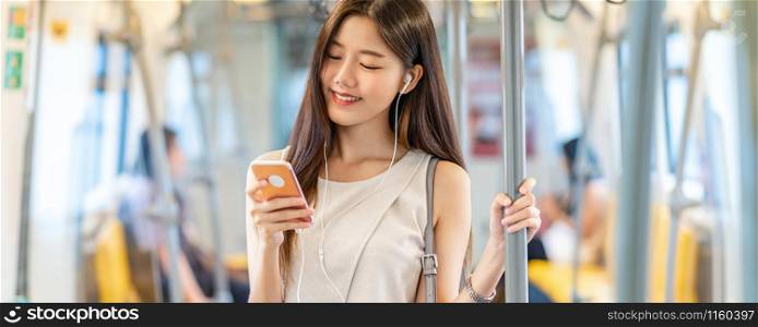 Banner, web page or cover template of Young Asian woman passenger using and listening music via smart mobile phone in subway train station, japanese,chinese,Korean lifestyle, leisure and daily life,