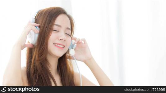 Banner website beautiful portrait asian young woman happy enjoy and fun listen music with headphone sitting in living room, lifestyle of girl relax sound radio with earphone, leisure and technology concept.