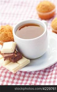 bar of chocolate,tea and muffin on plaid fabric