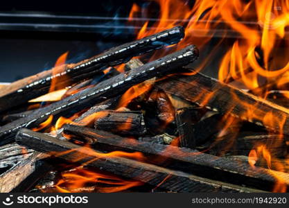 Barbecue grill pit with glowing and flaming hot open fire with red flame, hot charcoal briquettes and embers