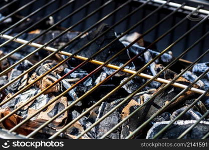 Barbecue grill pit with glowing and flaming hot open fire with red flame, hot charcoal briquettes and embers