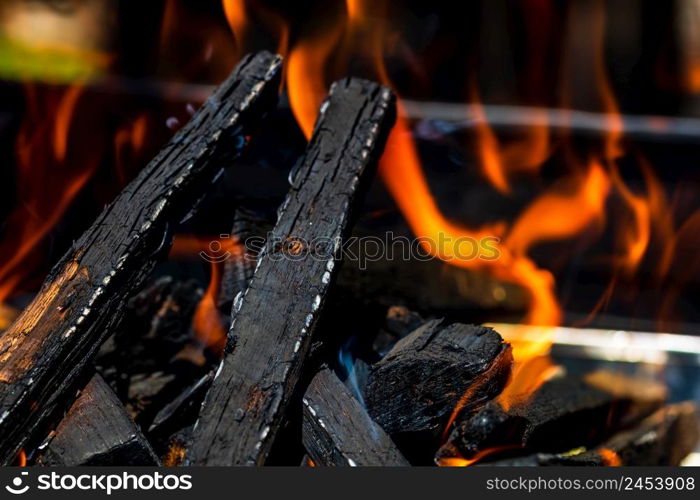 Barbecue grill pit with glowing and flaming hot open fire with red flame, hot charcoal briquettes and embers