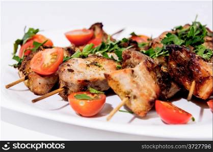 Barbecue on skewers, garnished with cherry om white plate