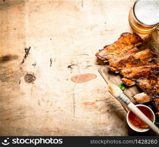Barbecue pork ribs with tomato sauce and beer. On wooden background.. Barbecue pork ribs with tomato sauce and beer.