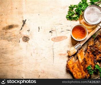 Barbecue pork ribs with tomato sauce and beer. On wooden background.. Barbecue pork ribs with tomato sauce and beer.