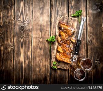 Barbecue ribs with a cold beer. On a wooden table.. Barbecue ribs with a cold beer.