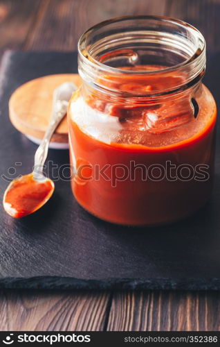 Barbecue sauce in the glass jar on the black stone board