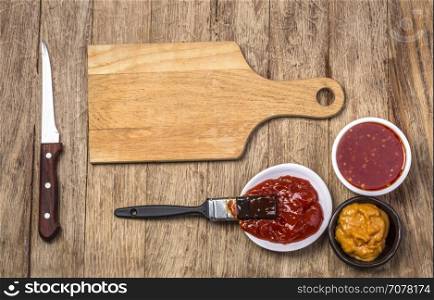 Barbecue sauce with basting brush over rustic barn wood table with room for copy space.