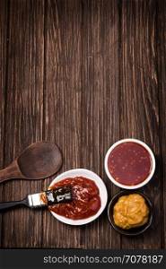 Barbecue sauce with basting brush over rustic barn wood table with room for copy space.