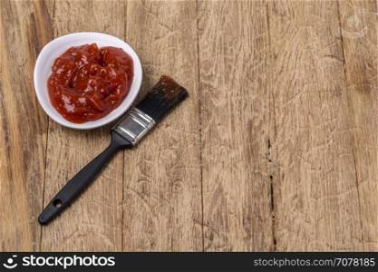 Barbecue sauce with basting brush over wooden table with room for copy space.