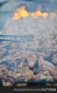 Barbecue with chicken on grill, fire and smoke in background