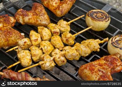 barbecue with chicken wings, meat skewer and ham