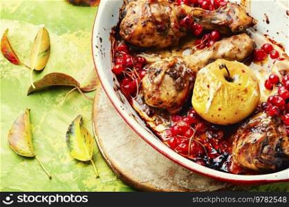 Barbecued chicken drumsticks in a baking dish with apple and berries. Autumn meat recipe.. Chicken legs with apple and berries in the oven dish