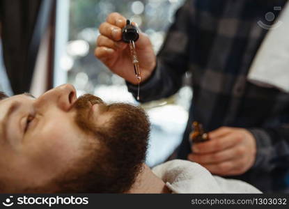 Barber and customer, beard cutting closeup. Professional barbershop is a trendy occupation. Male hairdresser and client in hair salon. Barber and customer, beard cutting closeup