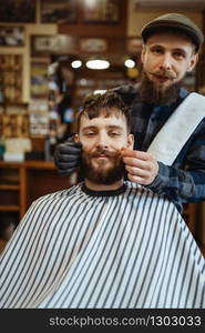 Barber and customer with a mustache, old school beard cutting. Professional barbershop is a trendy occupation. Male hairdresser and client in retro style hairdressing salon. Barber and customer with a mustache, barbershop