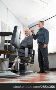 Barber brushing business mans head in barber shop