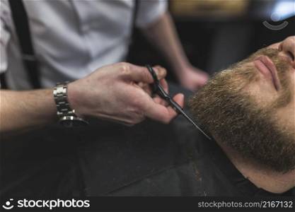 barber cutting beard crop client
