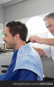 Barber cutting mans hair in barber shop