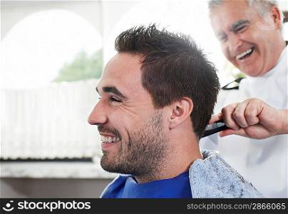 Barber cutting mans hair in barber shop close-up