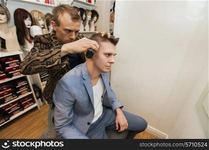 Barber shaving male customer&rsquo;s hair in shop