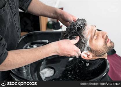 Barber shop. Hairdresser man washes client head in barbershop. High quality photography. Barber shop. Hairdresser man washes client head in barbershop